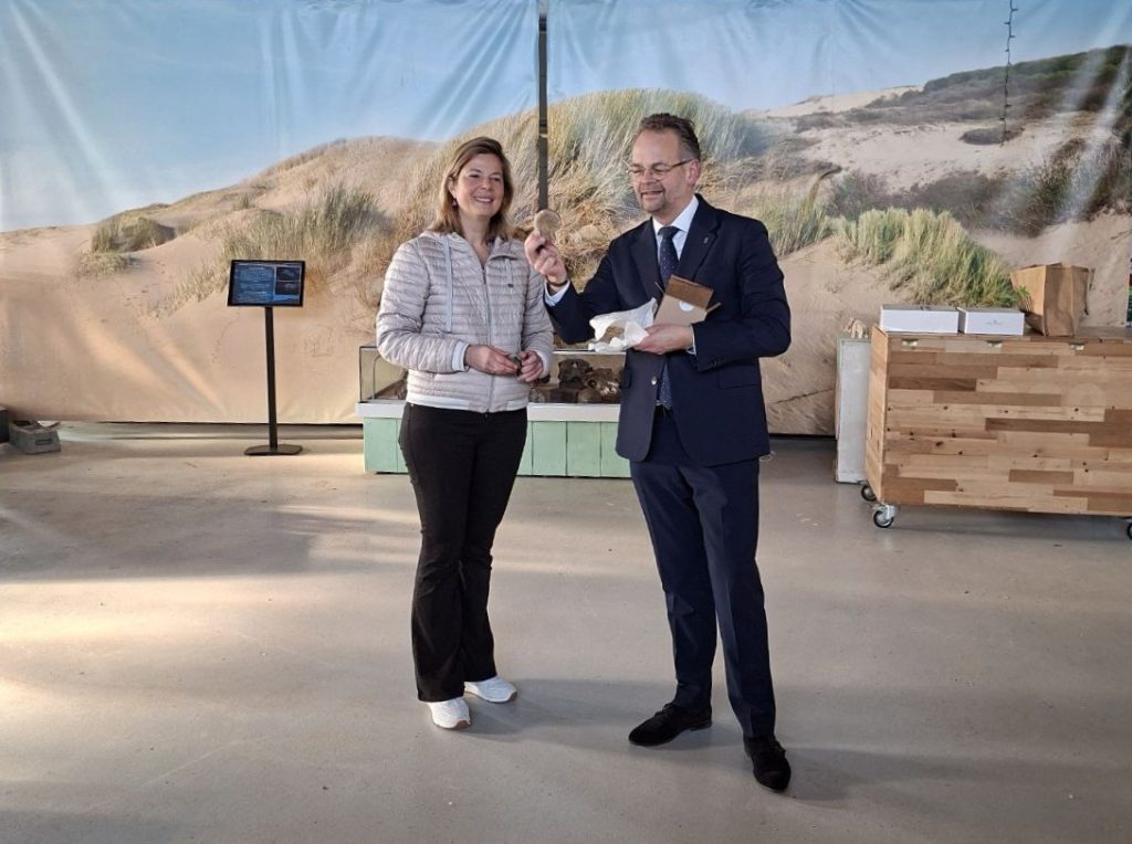 Jacco Knape krijgt een cadeautje bij natuurcentrum Katwijk, naast een vrouw voor een duinexpositie
